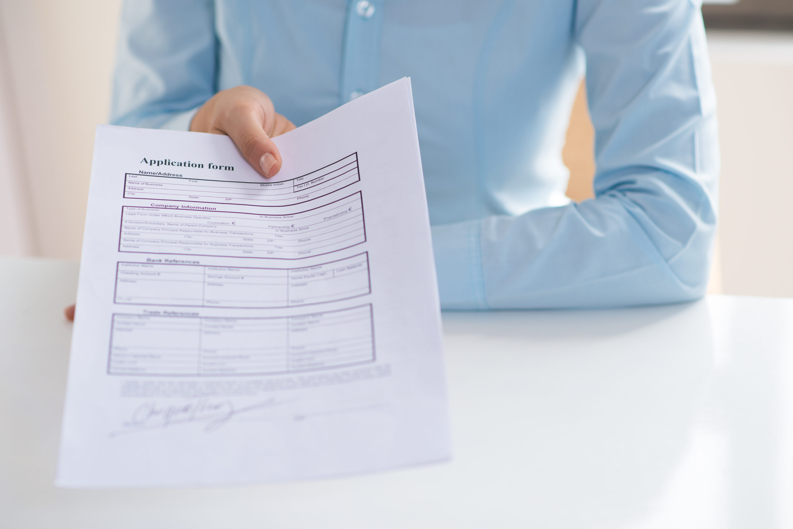 closeup of person giving signed application form to viewer