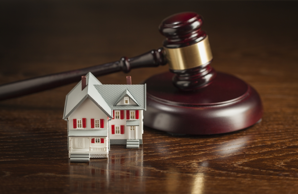 gavel and small model house on wooden table.